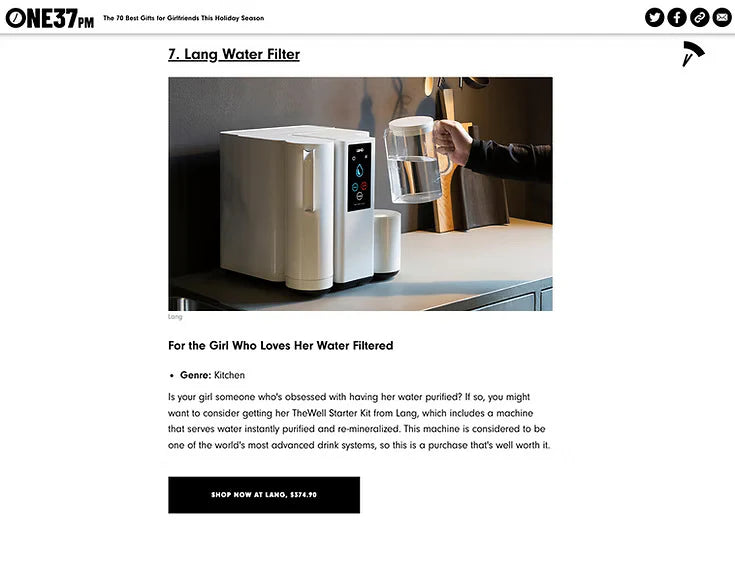 Water filter machine on a counter with a hand holding a clear container, displayed on a magazine or article page.
